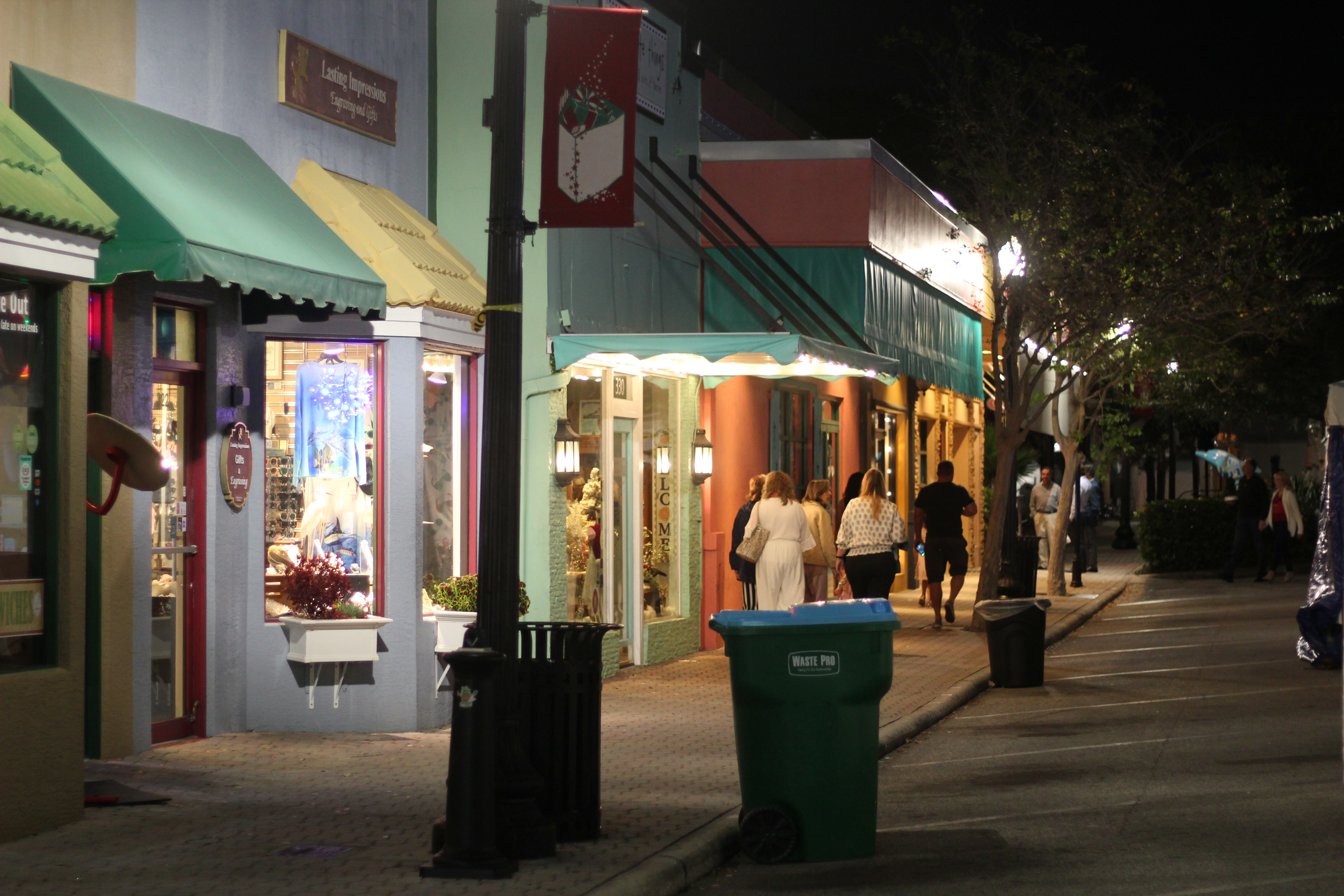 Dunedin Main Street at night with colorful storefronts and pedestrians