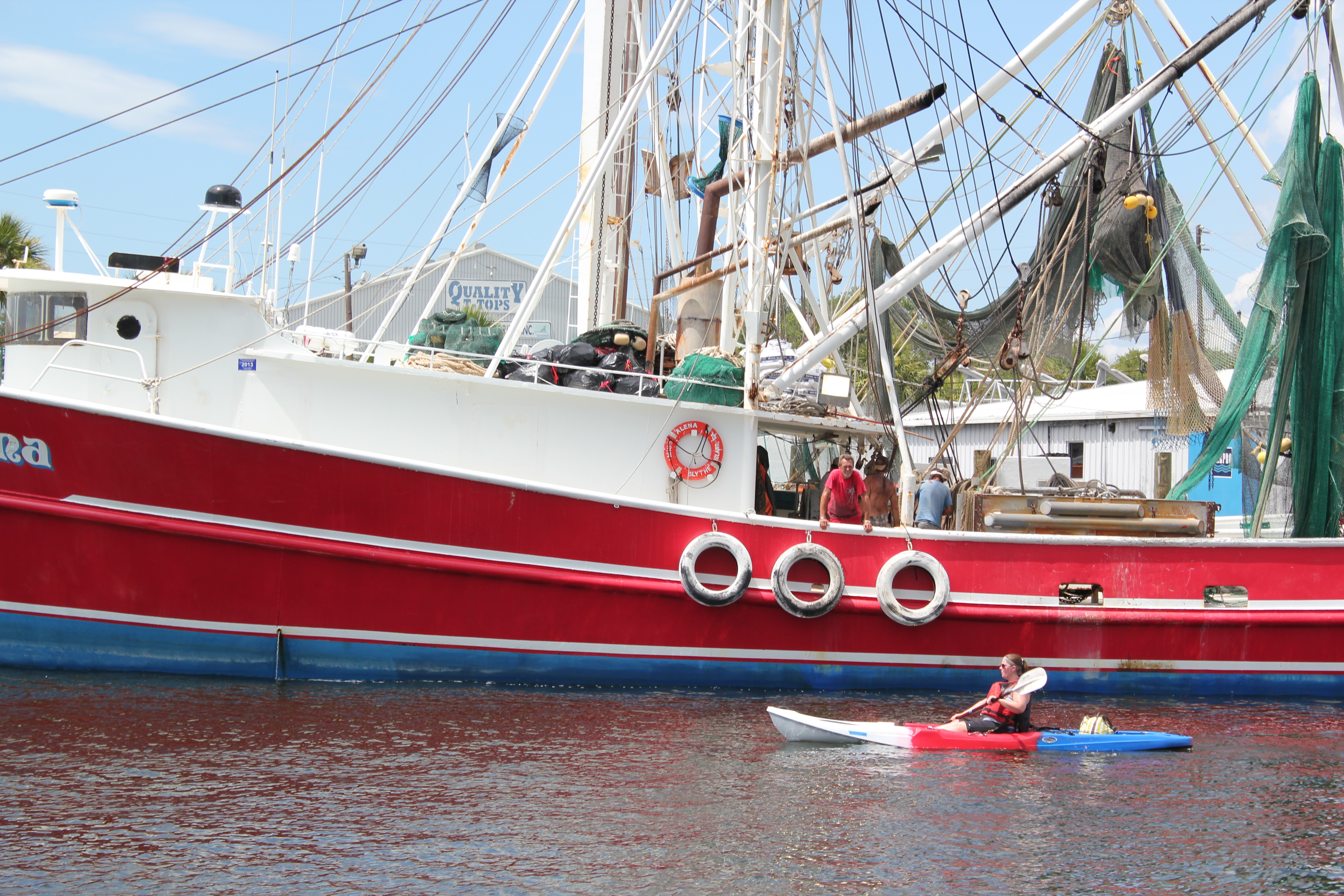 Kayaker paddling past a shrimp boat on the Anclote River in Tarpon Springs